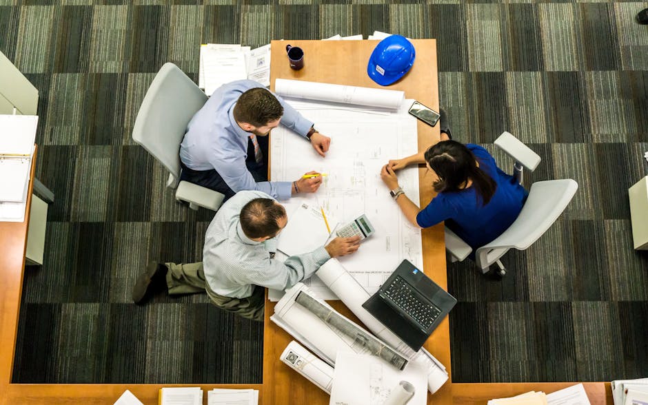 Business & Management Course Top view of a team working on construction plans in an office setting.